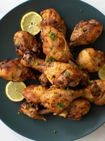 Instant pot drumsticks on a plate with lemon slices.