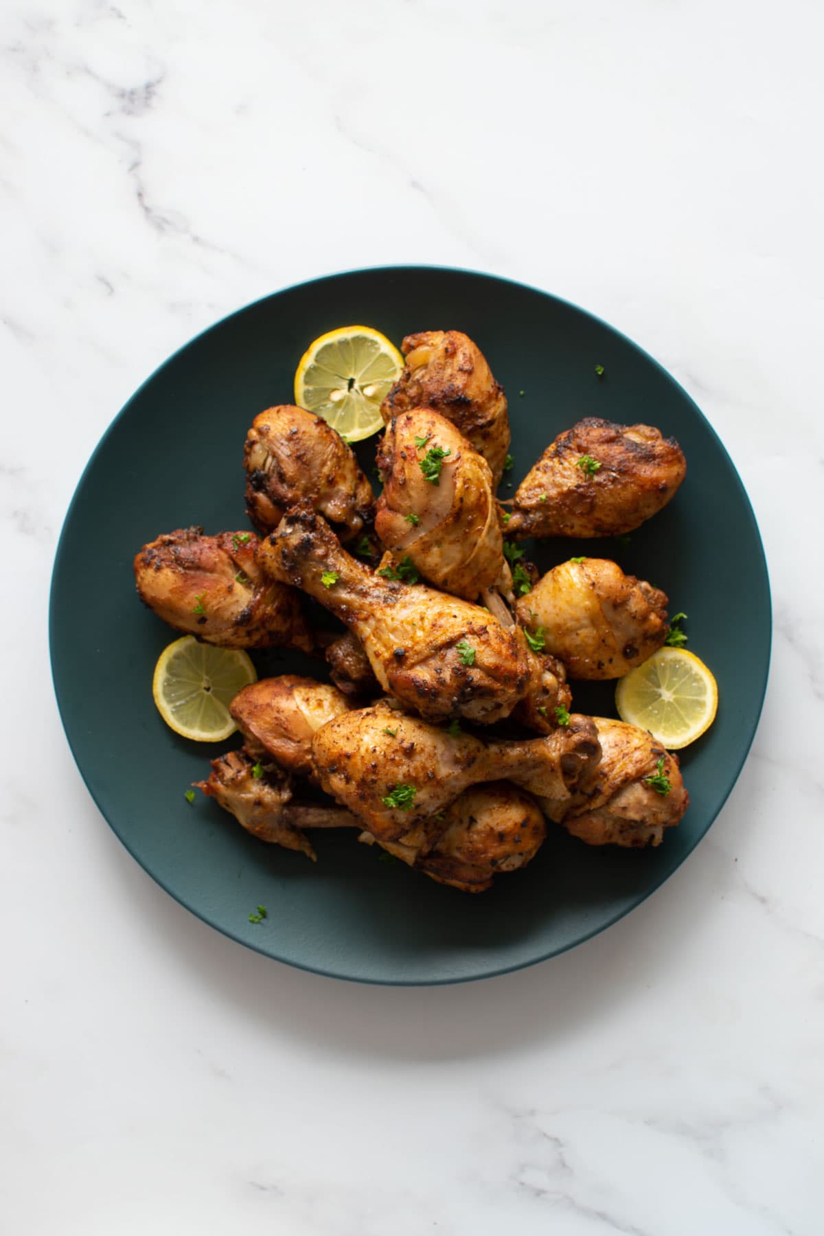 A plate with roasted chicken drumsticks.