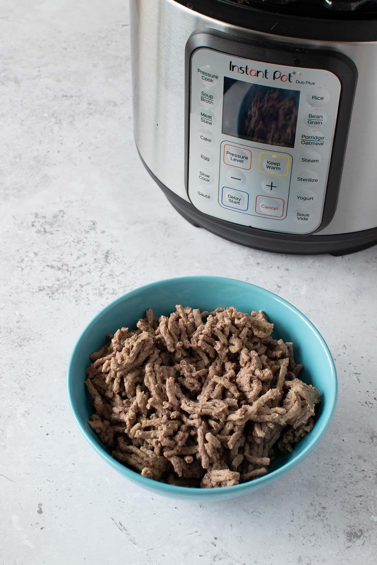 Cooked ground beef in front of an Instant Pot.