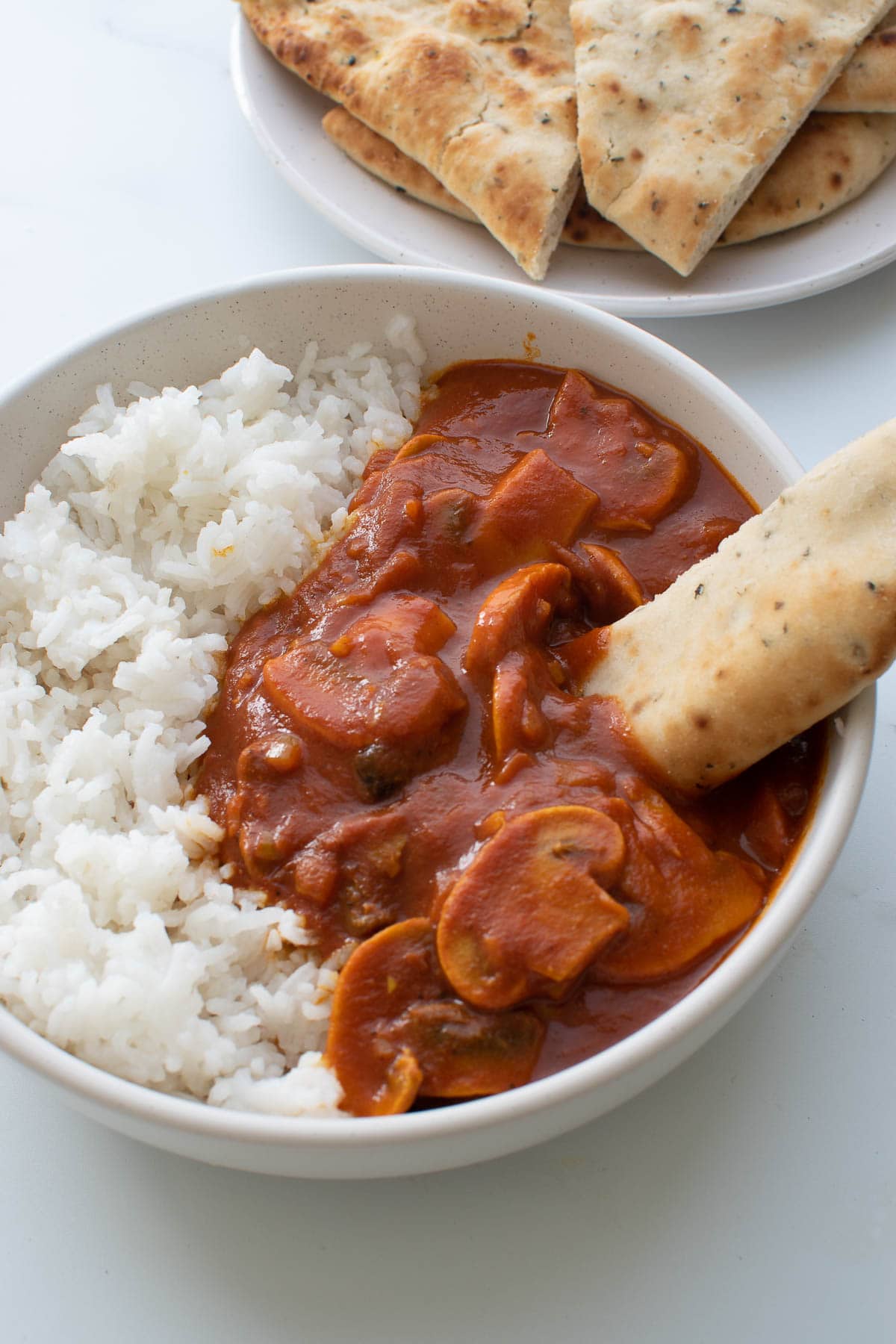 A piece of naan dipped into curry.