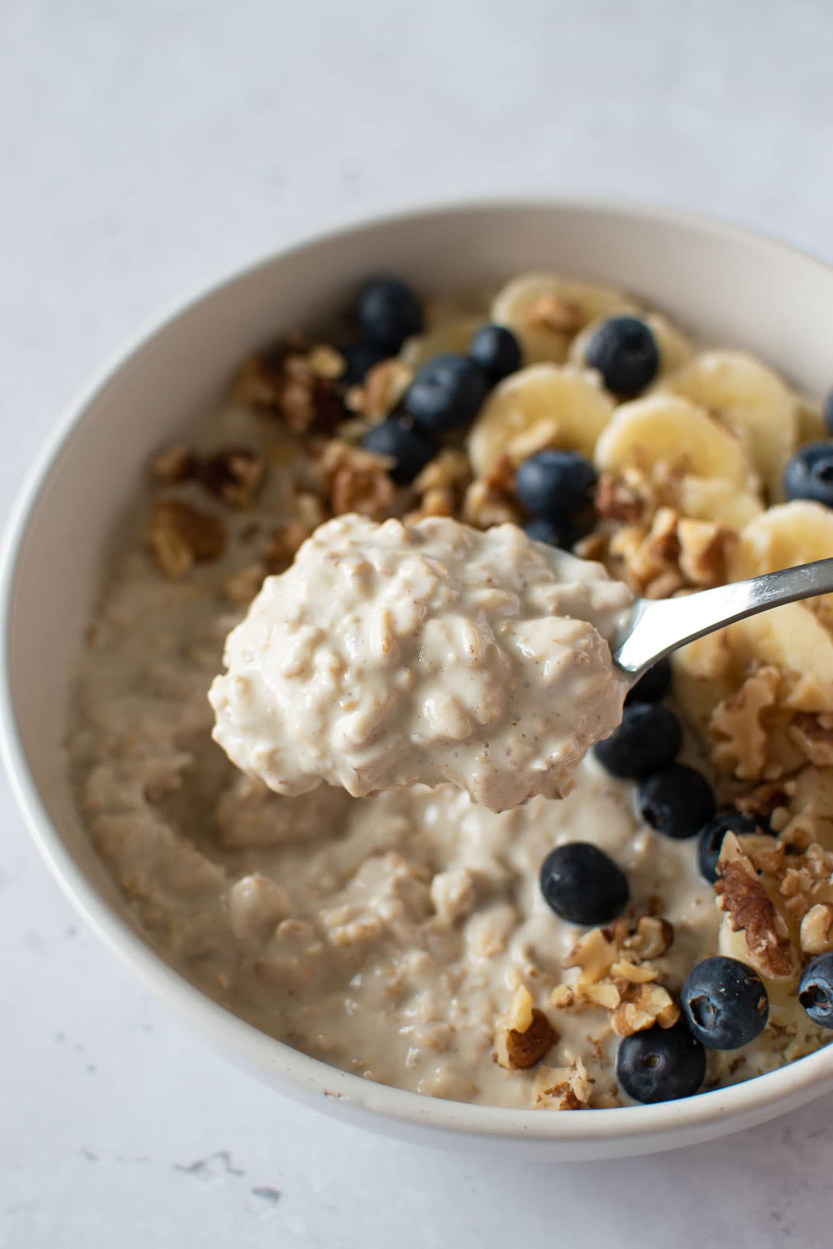 A spoon lifting up a serving of overnight oats.