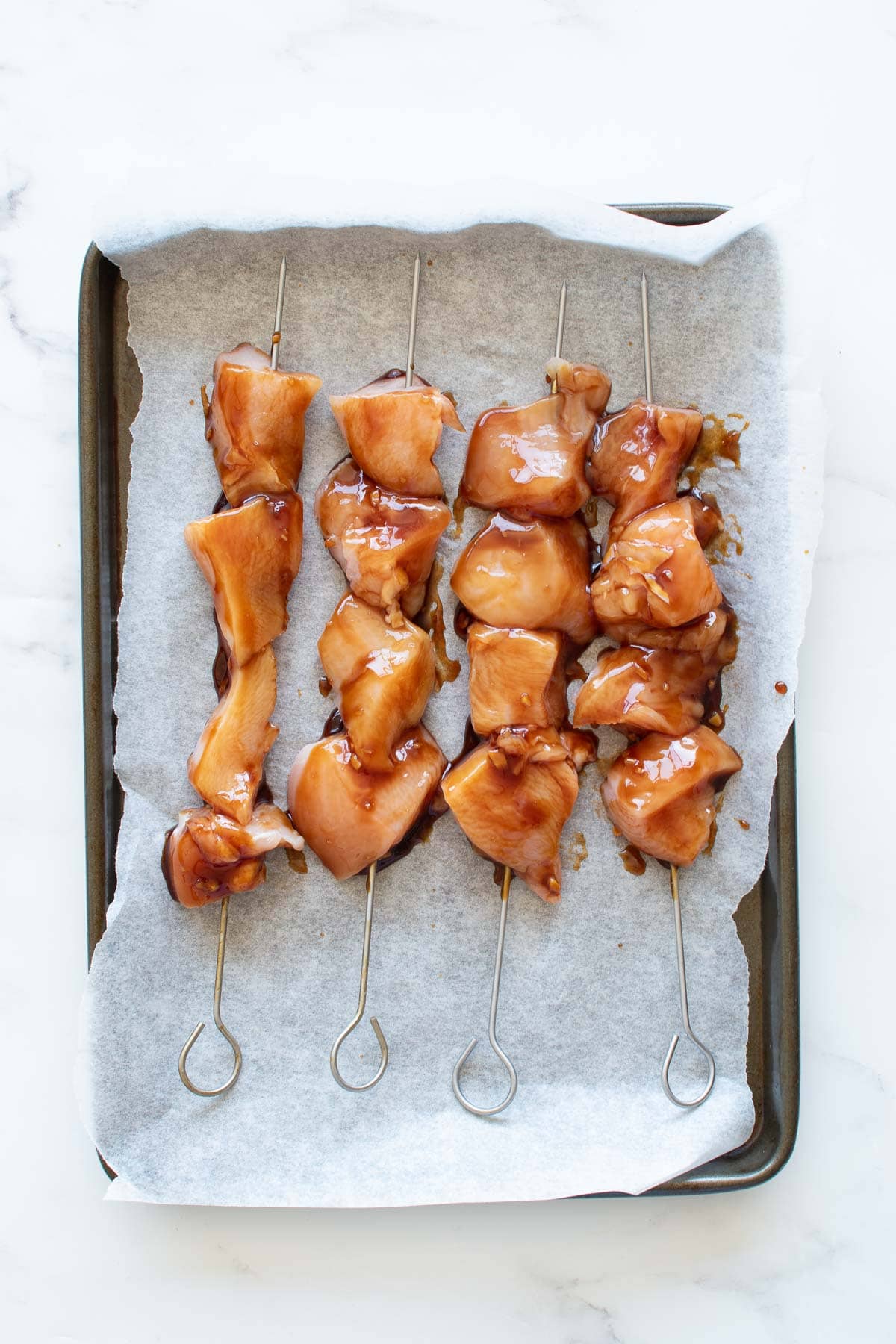 Uncooked chicken skewers with teriyaki sauce.