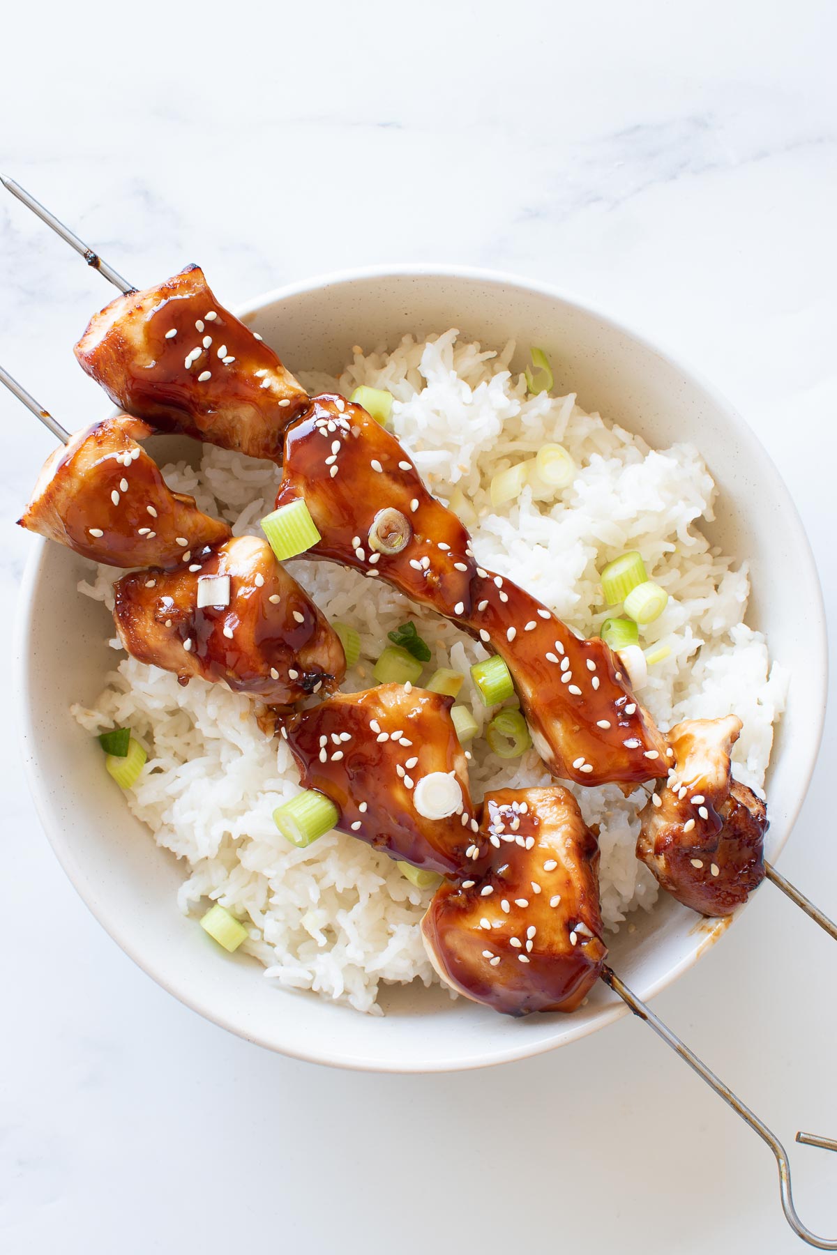 Teriyaki chicken skewers in a bowl with rice.