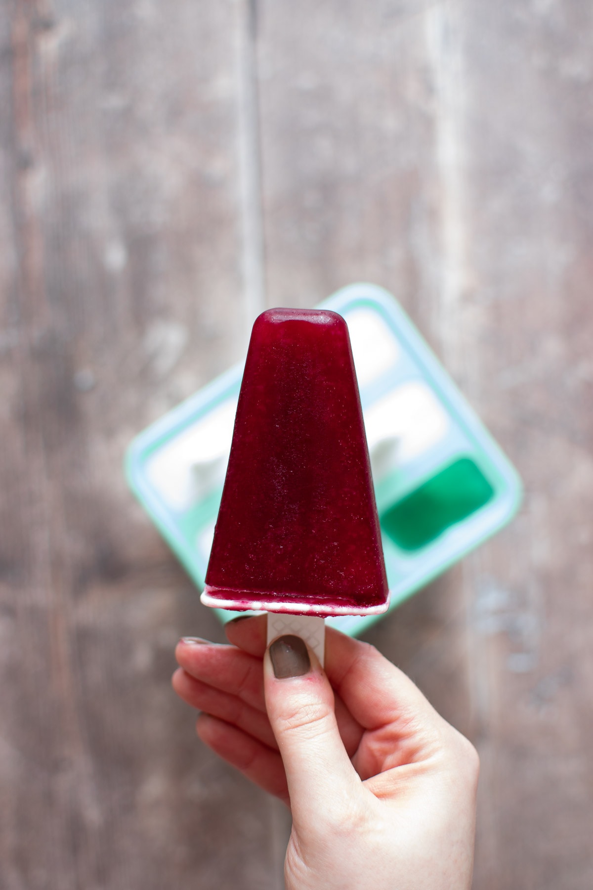 A hand holding a red wine popsicle.