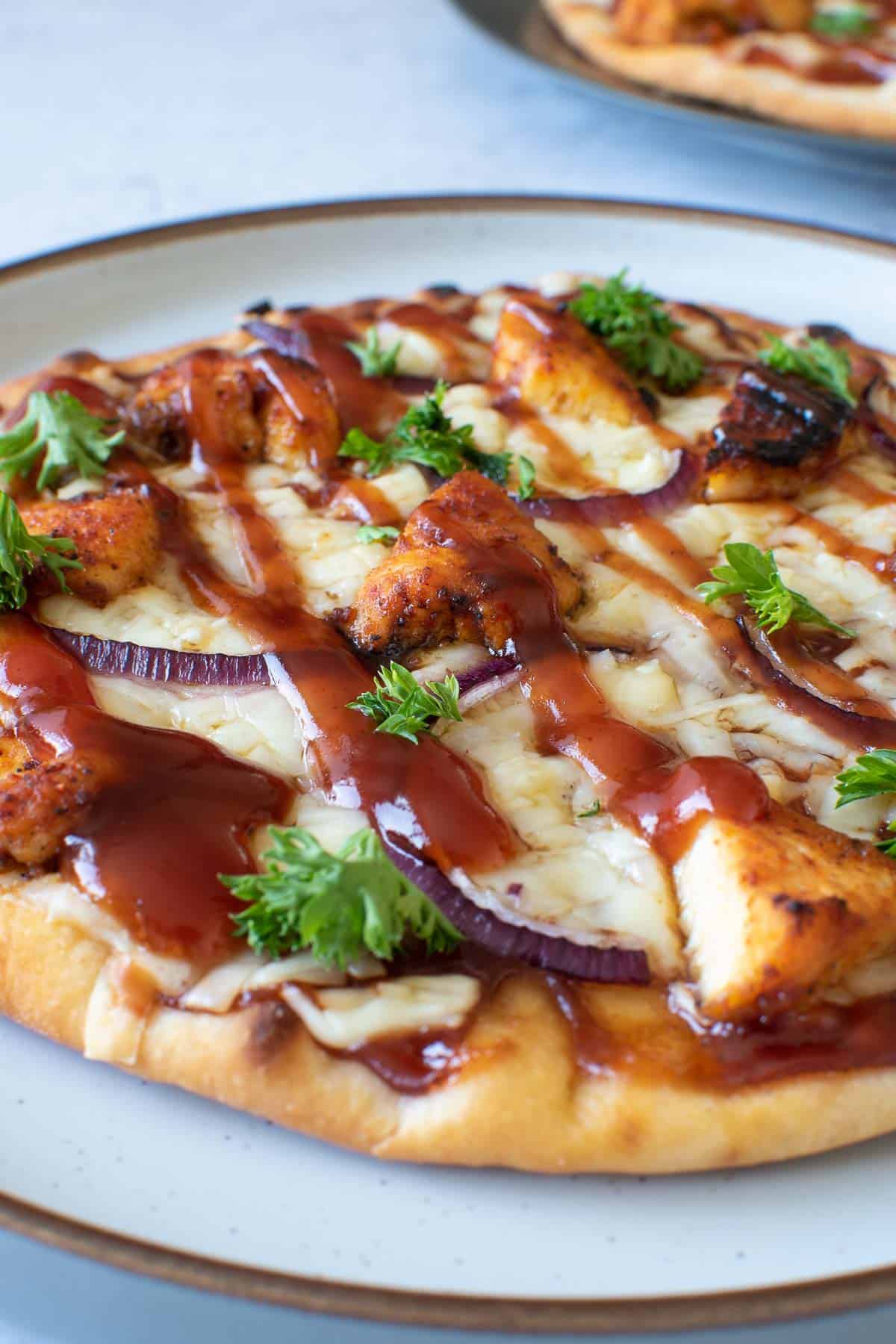 Closeup of flatbread with chicken and BBQ sauce.