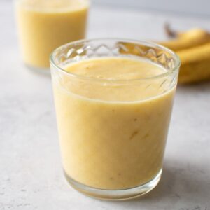 A glass with banana mango smoothie.