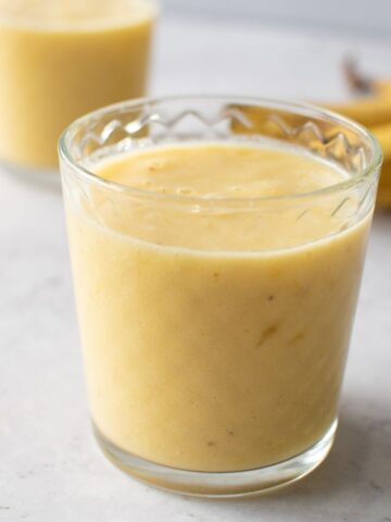 A glass with banana mango smoothie.