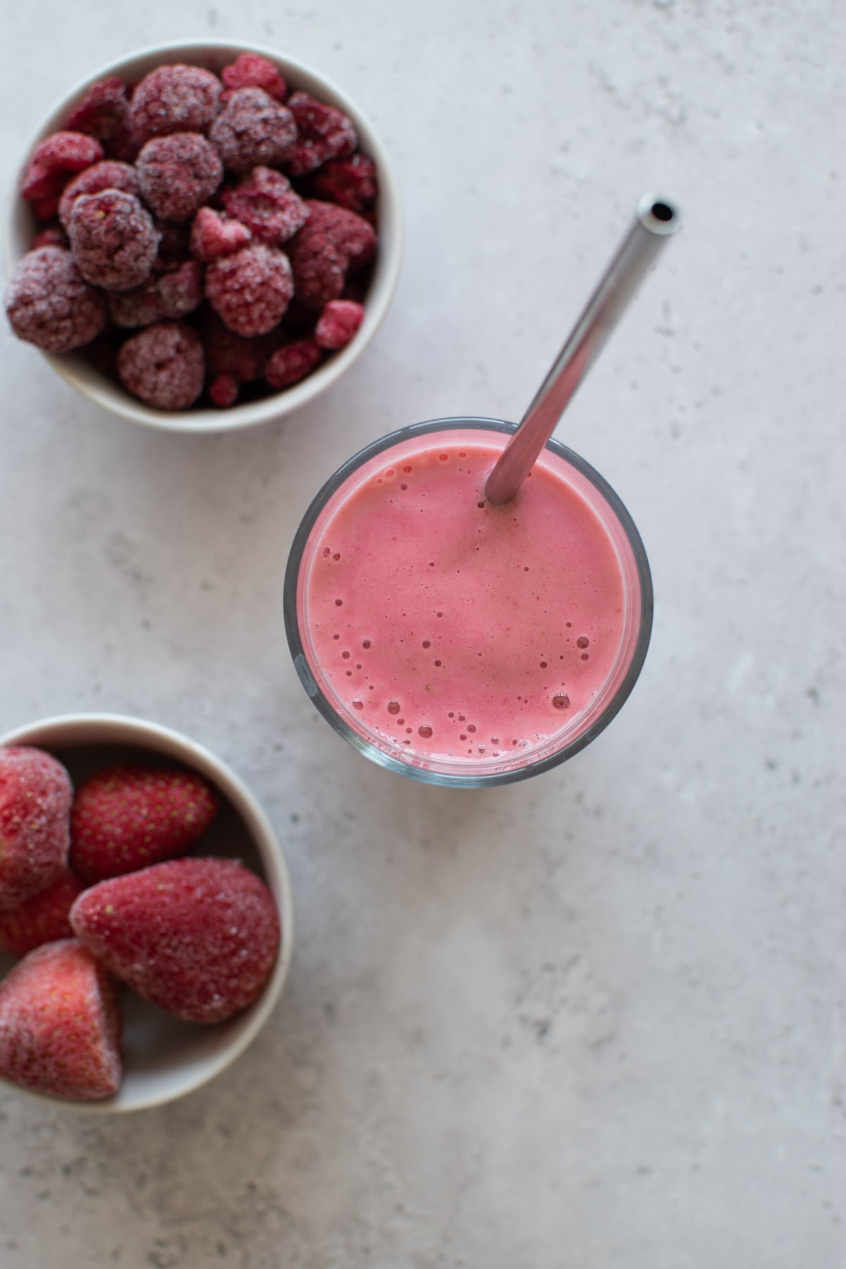 A glass of kefir smoothie with frozen berries on the side.