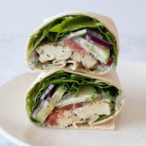 Close up of halloumi wraps with spinach, tzatziki and tomatoes.