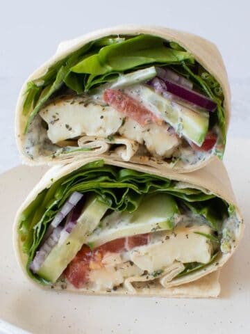 Close up of halloumi wraps with spinach, tzatziki and tomatoes.