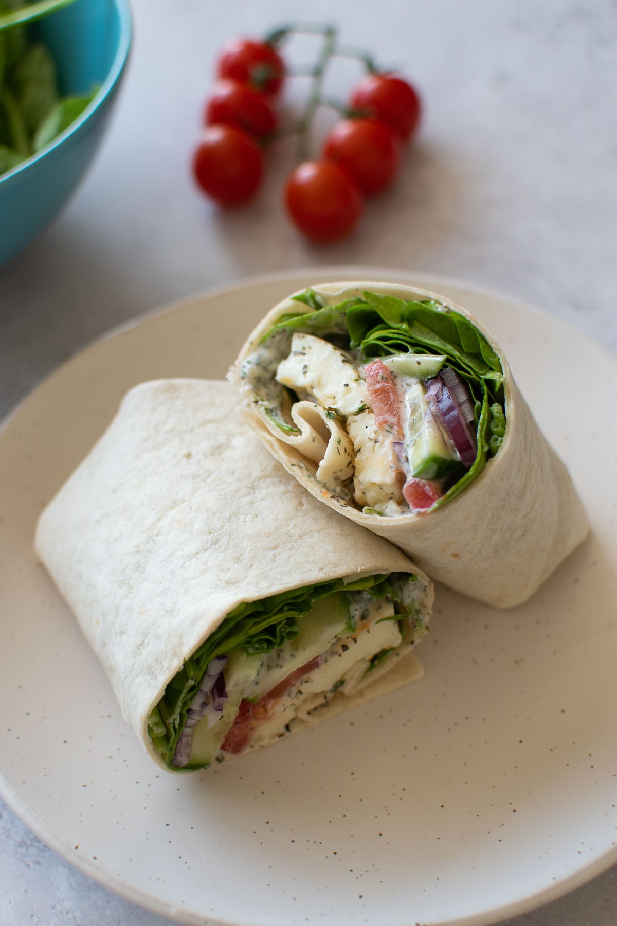 Halloumi wraps, with tomatoes and spinach in the background.