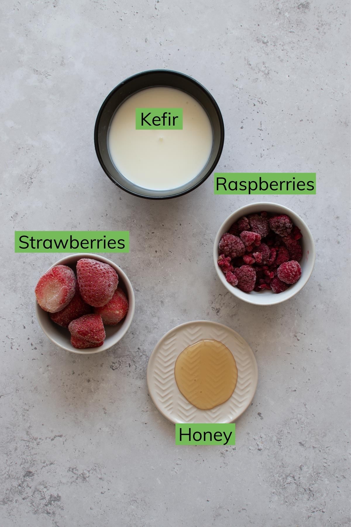 Frozen strawberries and raspberries, honey and kefir on a table.