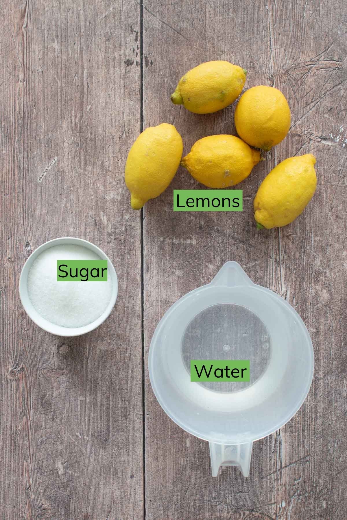 Lemons, sugar and water on a table.