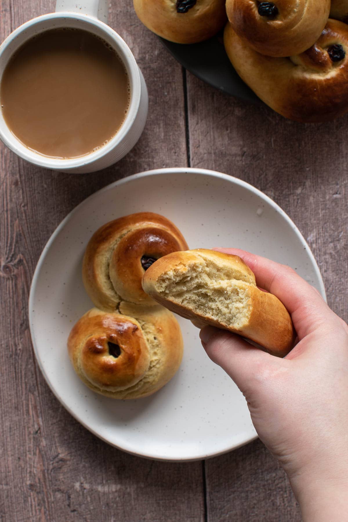 A hand holding lussekatter with a bite eaten off it.