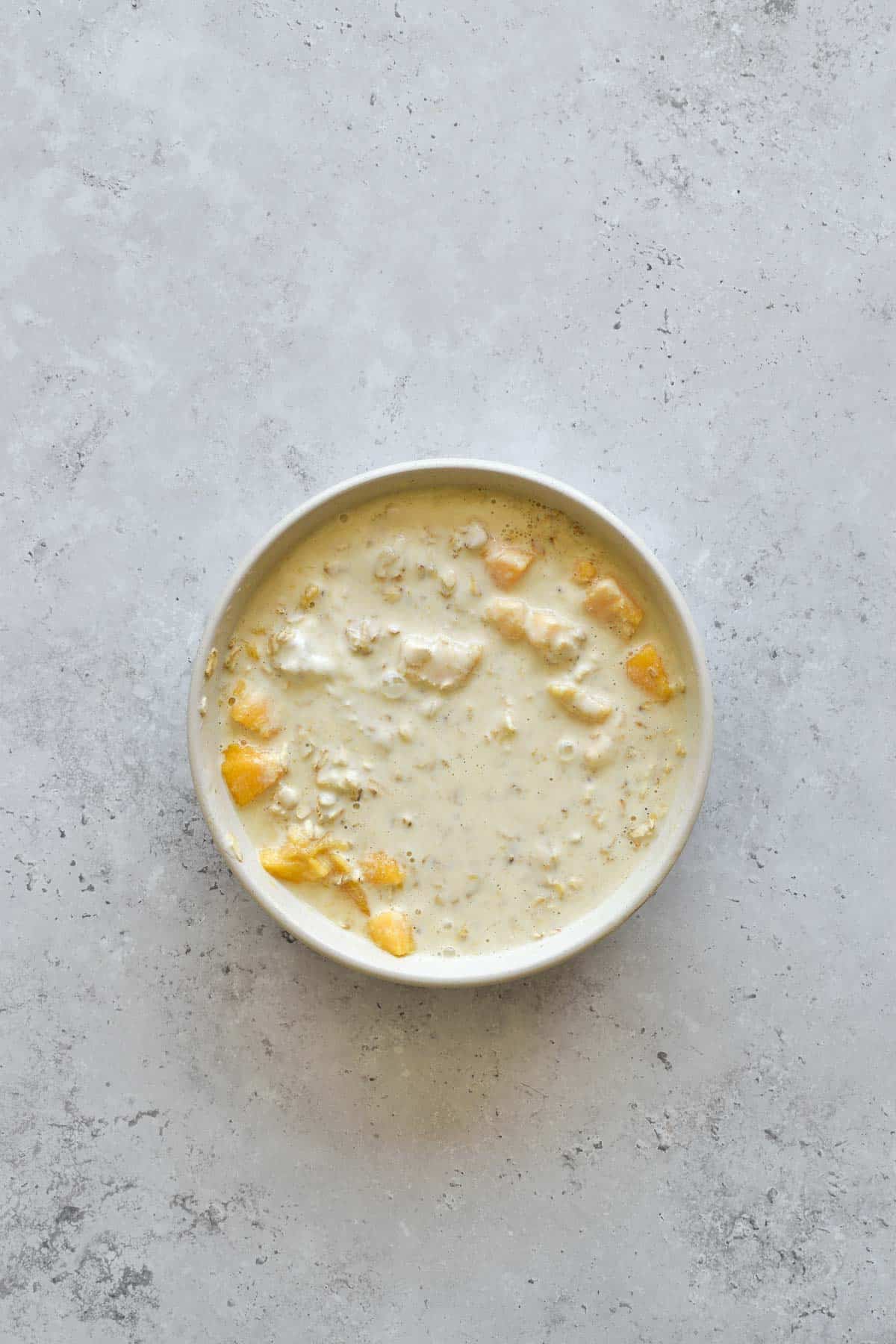 A bowl of oats, milk, yogurt and mango.