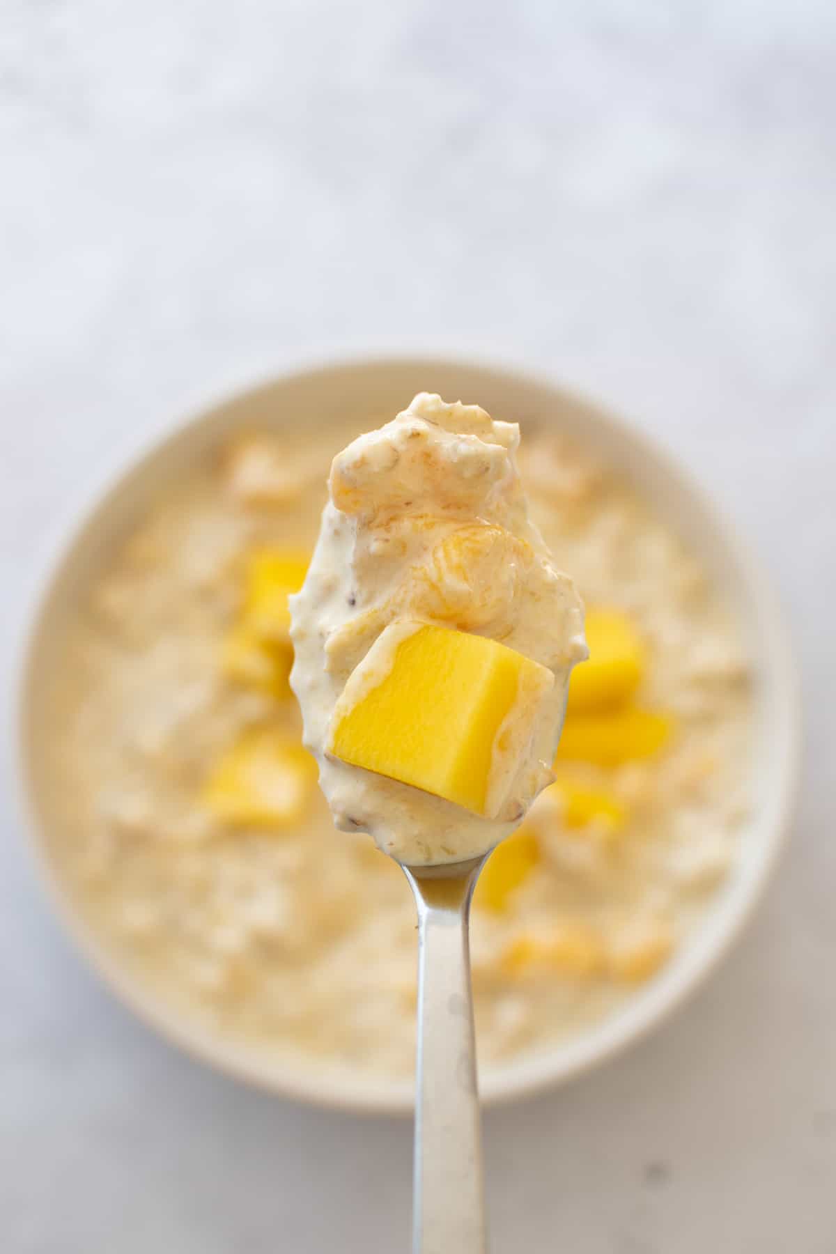 A spoon with mango and oats.