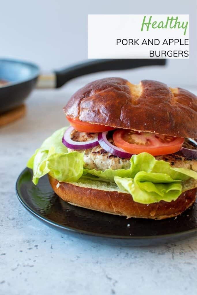 A pork burger in a bun, with tomatoes, lettuce and onions.