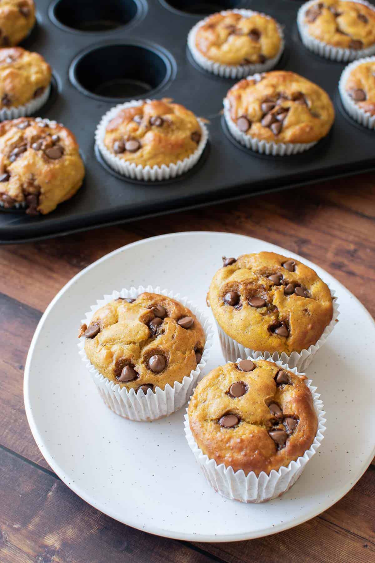 Plated pumpkin protein muffins, with a muffin pan in the background.