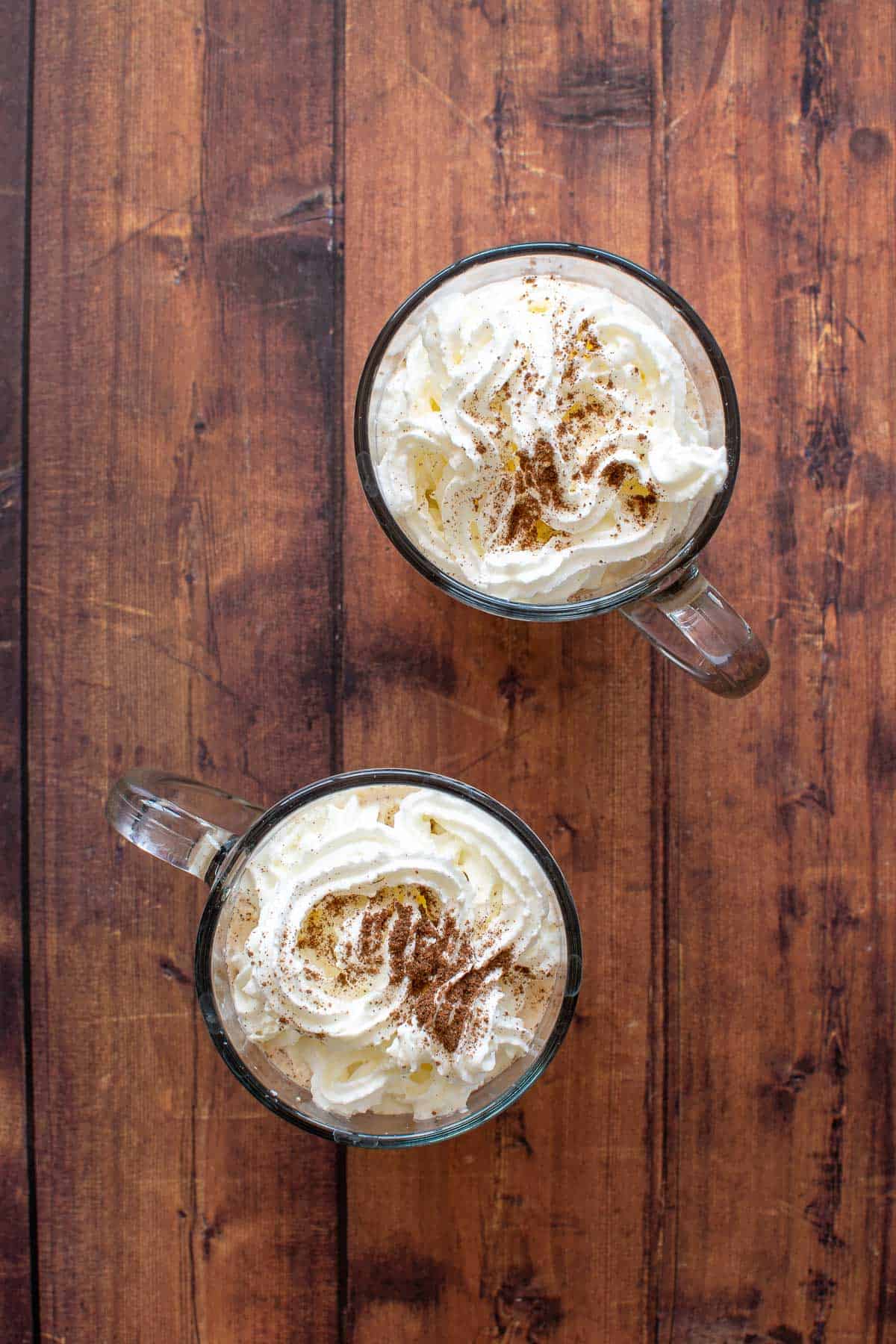 Overhead cups of latte with whipped cream.