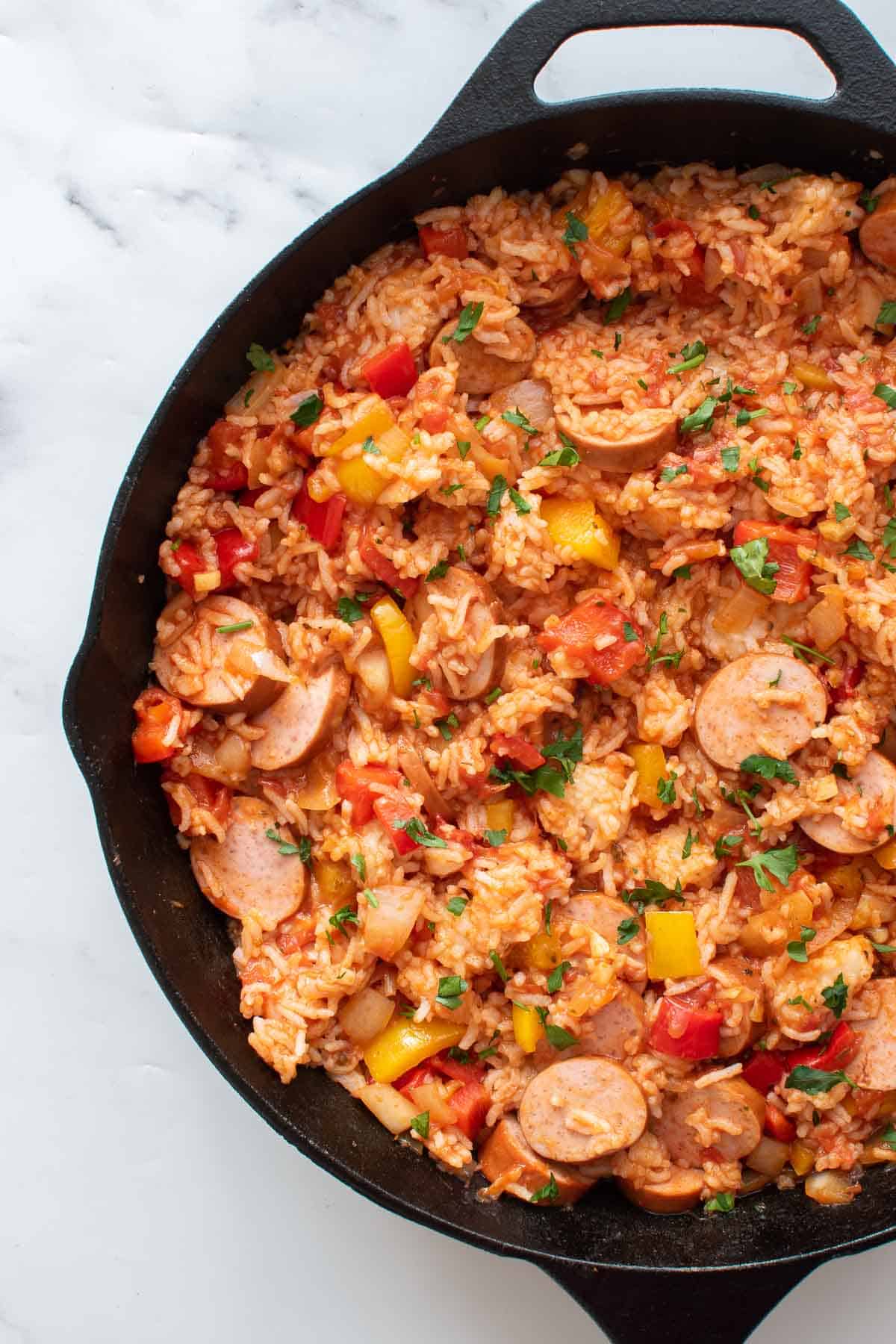 A cast iron pan with smoked sausage, rice and peppers.