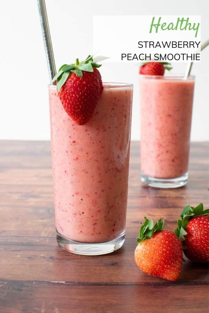 Side view of two glasses of stawberry peach smoothie. Two strawberries placed on the table.