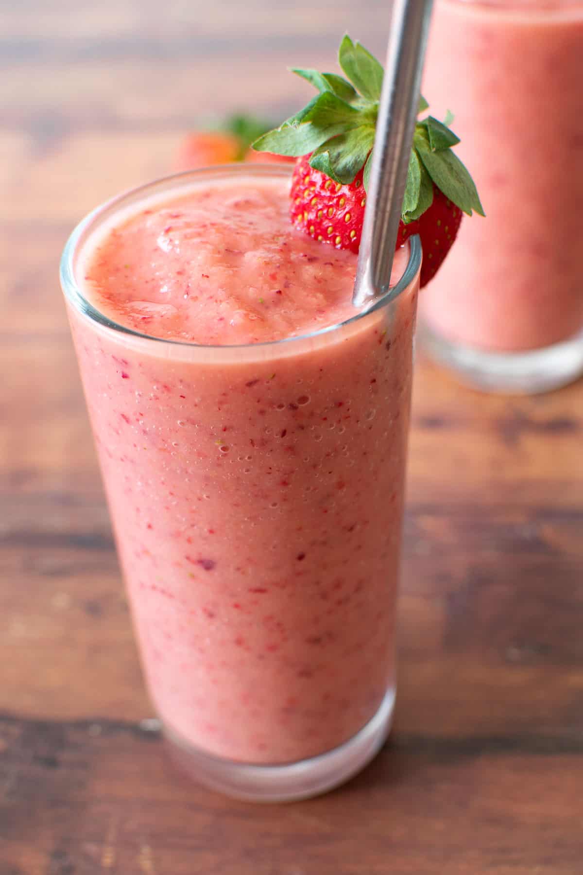 A glass of strawberry smoothie on a table.