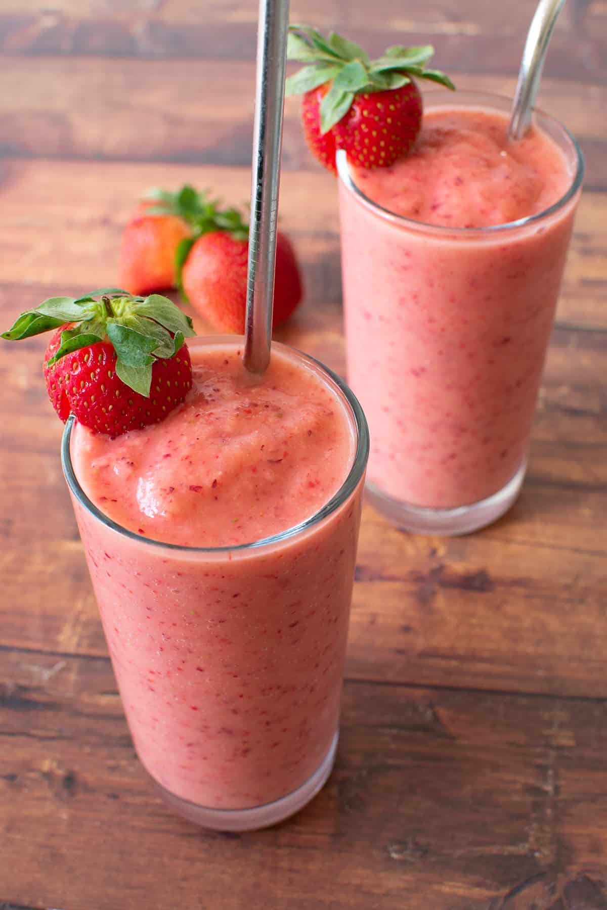 Two glasses of pink summer smoothies on a table.
