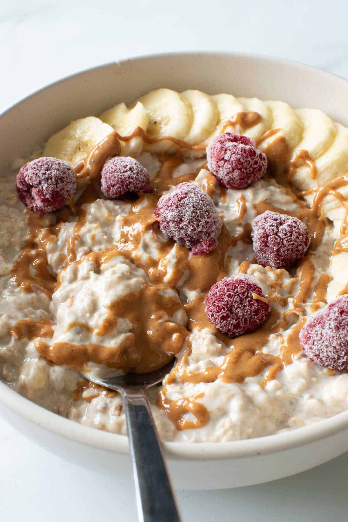 Refrigerator oatmeal with bananas. A spoon lifting out a portion.