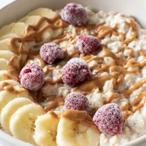 Banana overnight oats with sliced bananas, peanut butter and frozen raspberries.