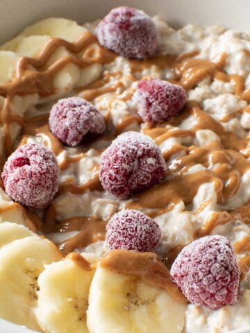 Banana overnight oats with sliced bananas, peanut butter and frozen raspberries.