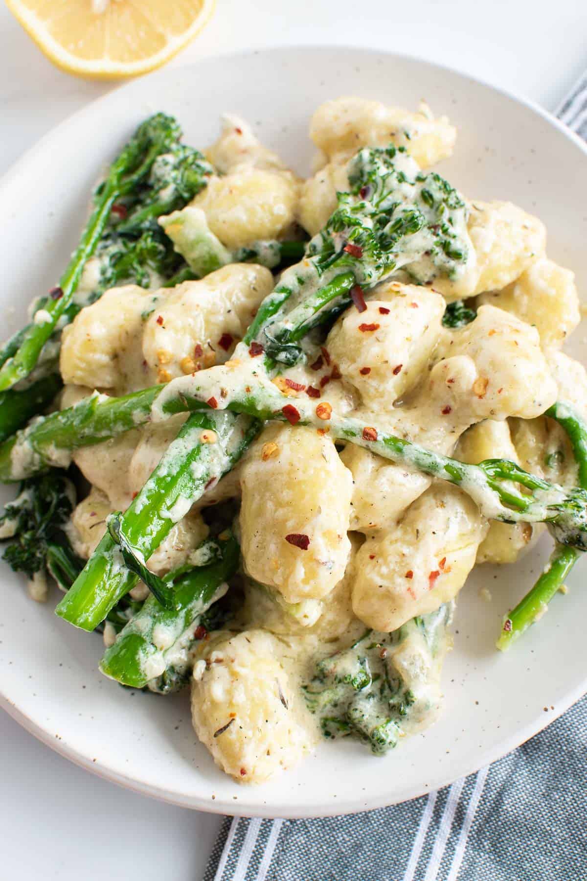 A plate with creamy gnocchi and broccoli.