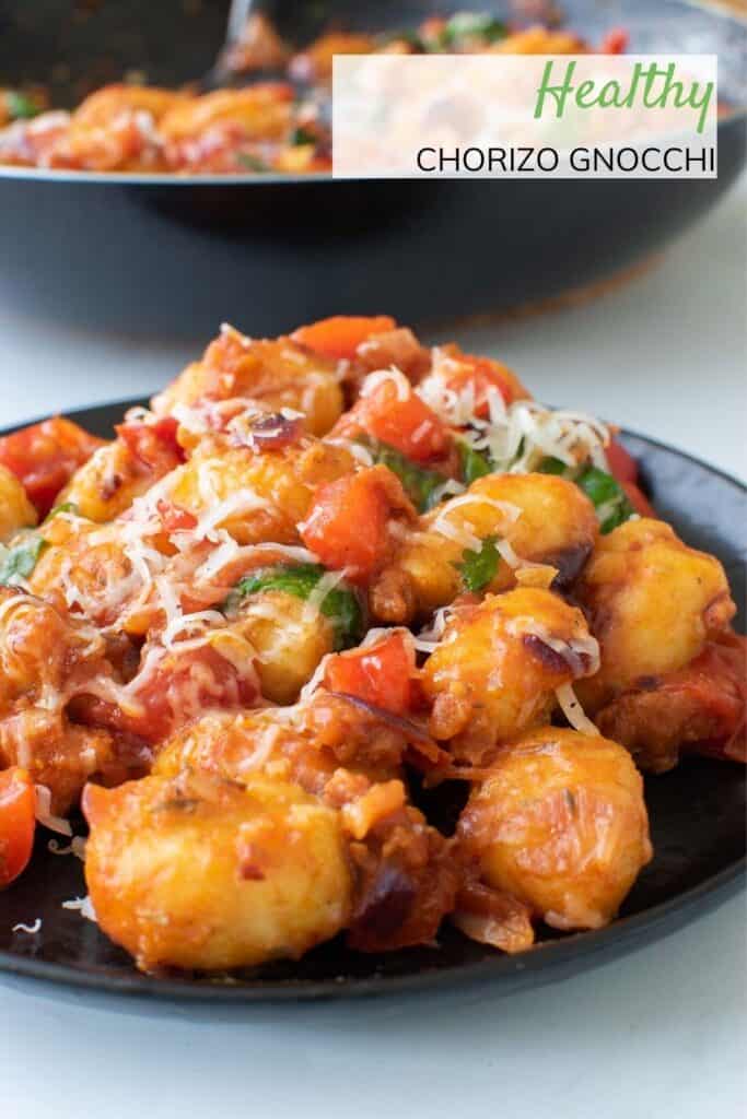 A plate of gnocchi with chorizo and tomatoes.