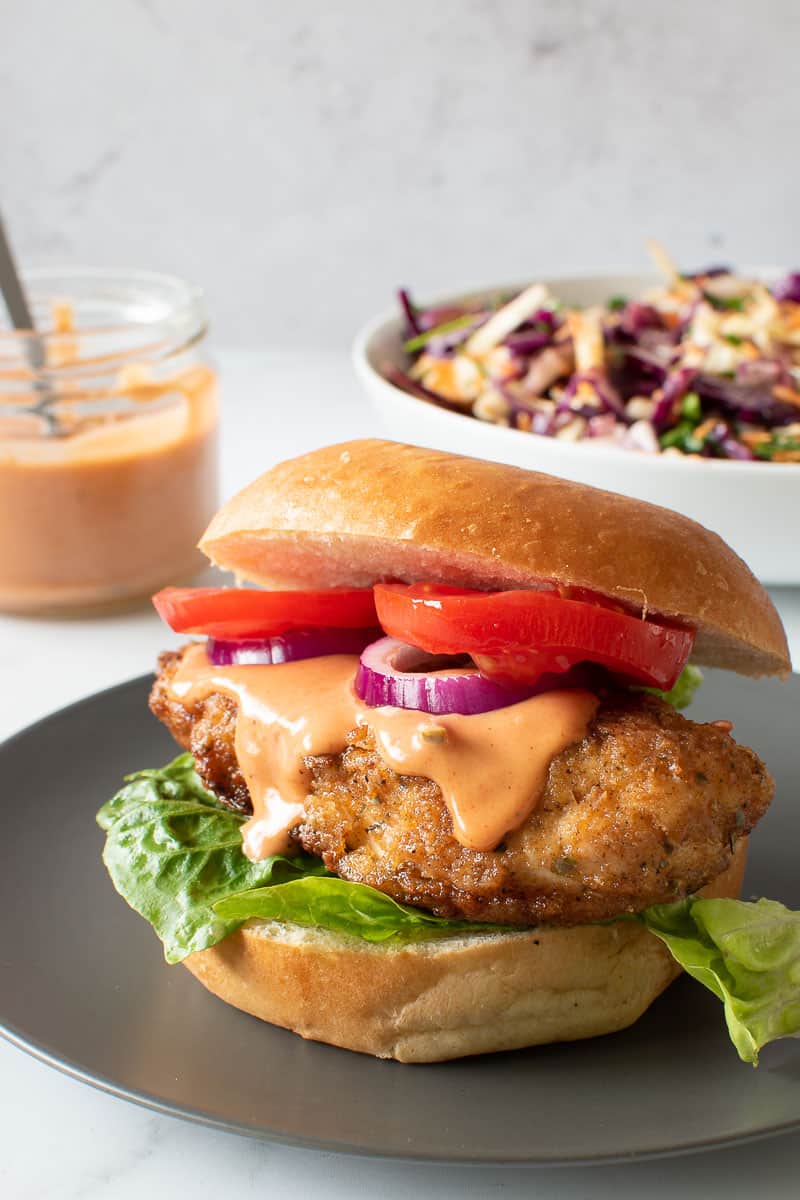 Chicken burger, with coleslaw and burger sauce in the background.