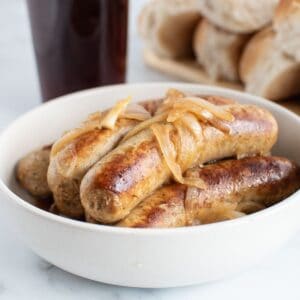 Close up of a bowl of brats and onions.