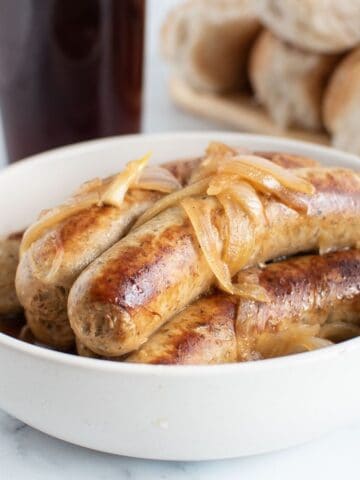 Close up of a bowl of brats and onions.