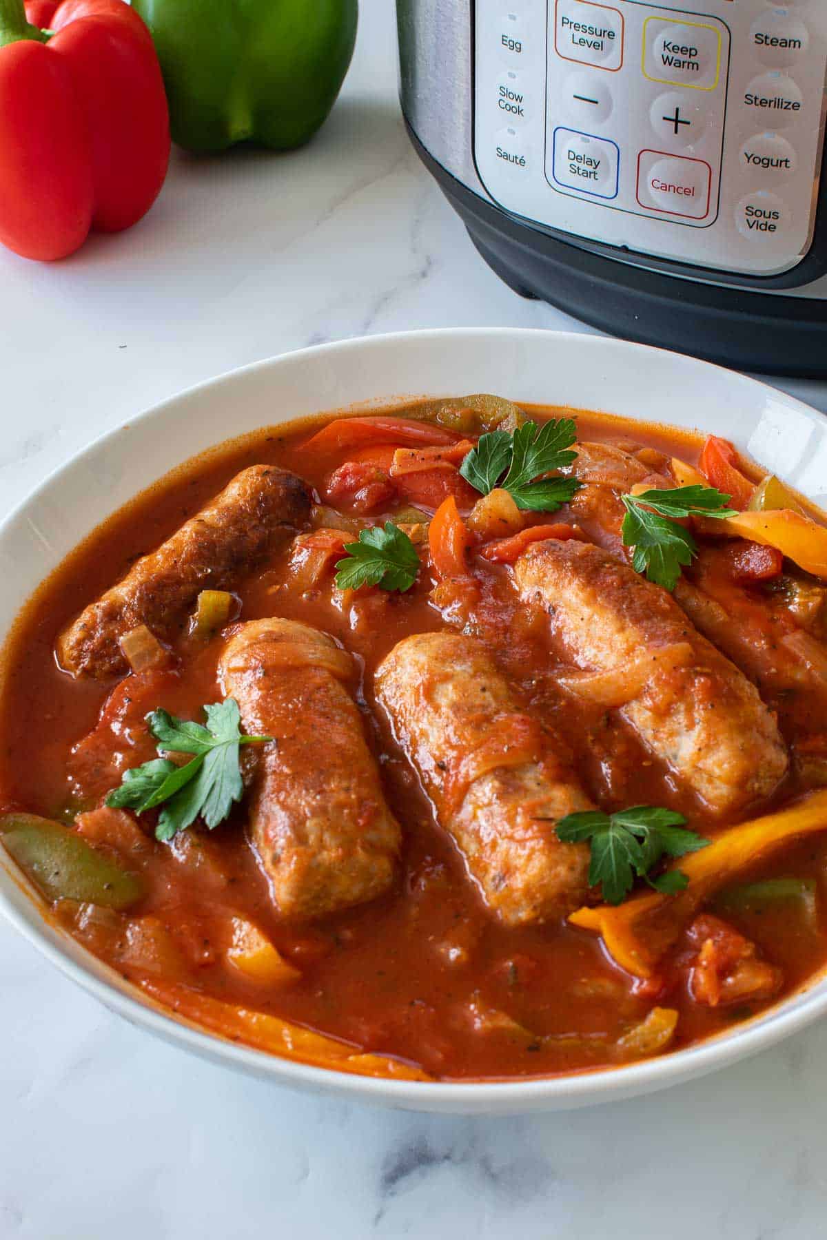 A large bowl of peppers, sausage and tomato sauce.