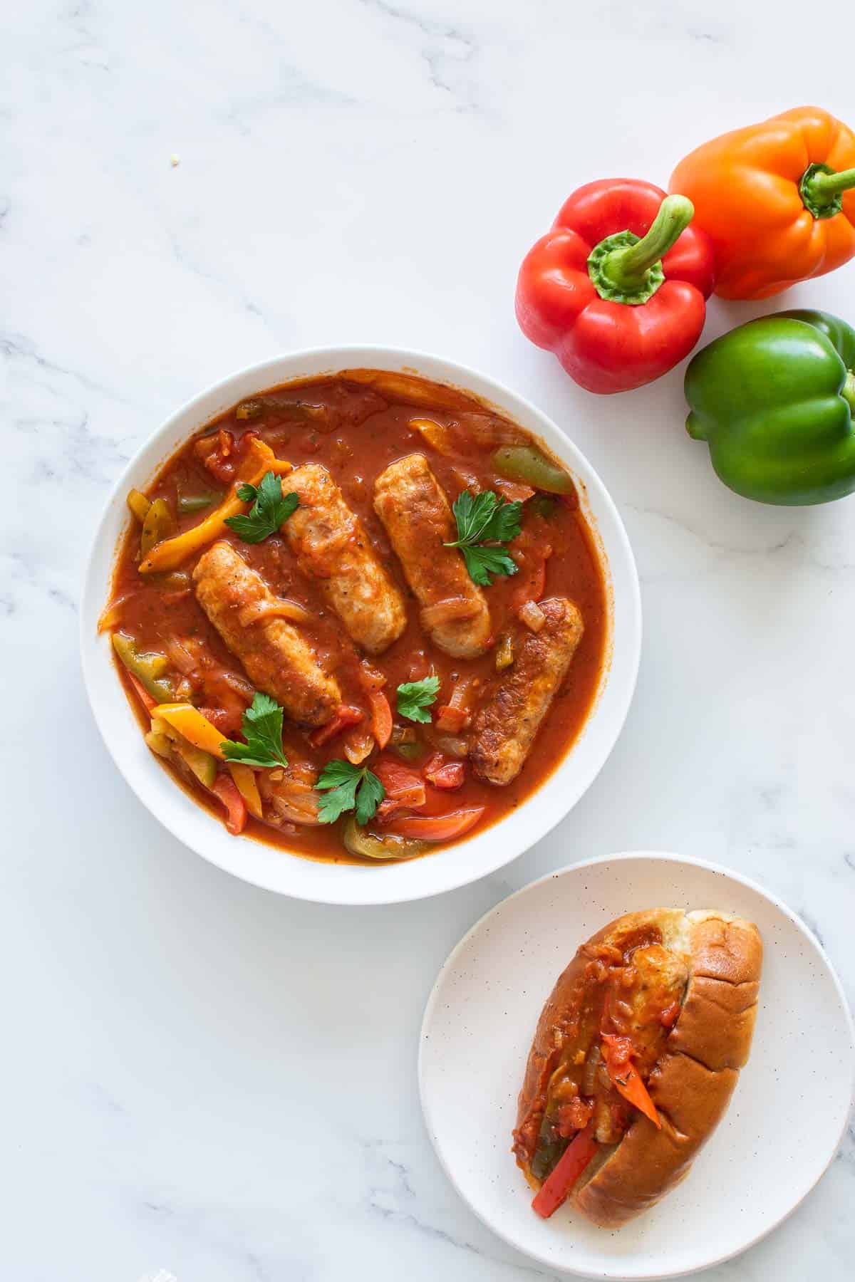 A bowl of peppers and sausage, with bell peppers on the side, and the dish served in a roll.