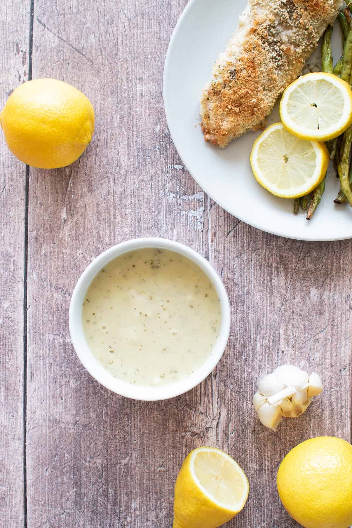 White sauce with lemon and garlic, with fish and lemon on the side.