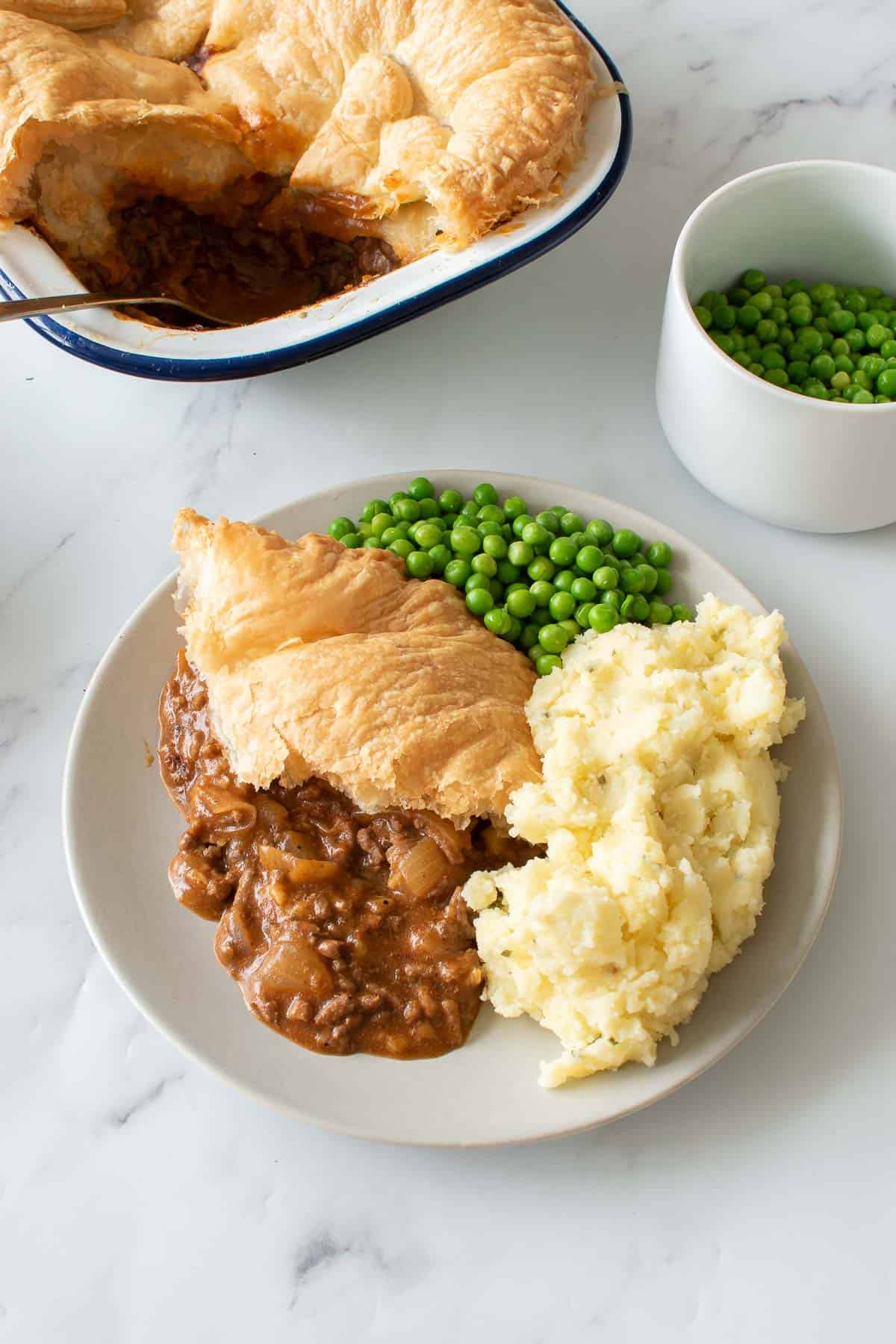 Peas, mash and pie on a plate.