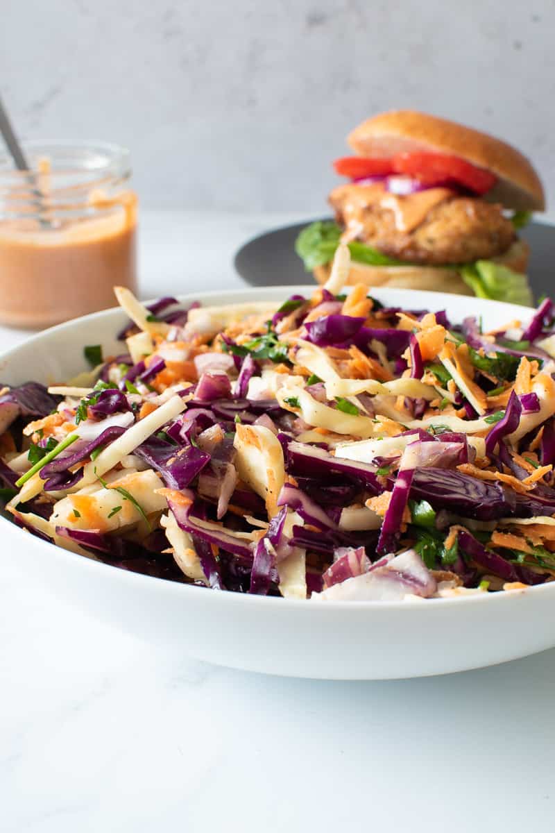 Coleslaw, burger and burger sauce on a table.