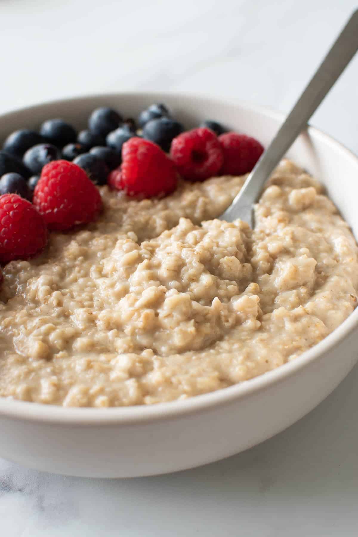 A spoon inserted into a bowl of oats.