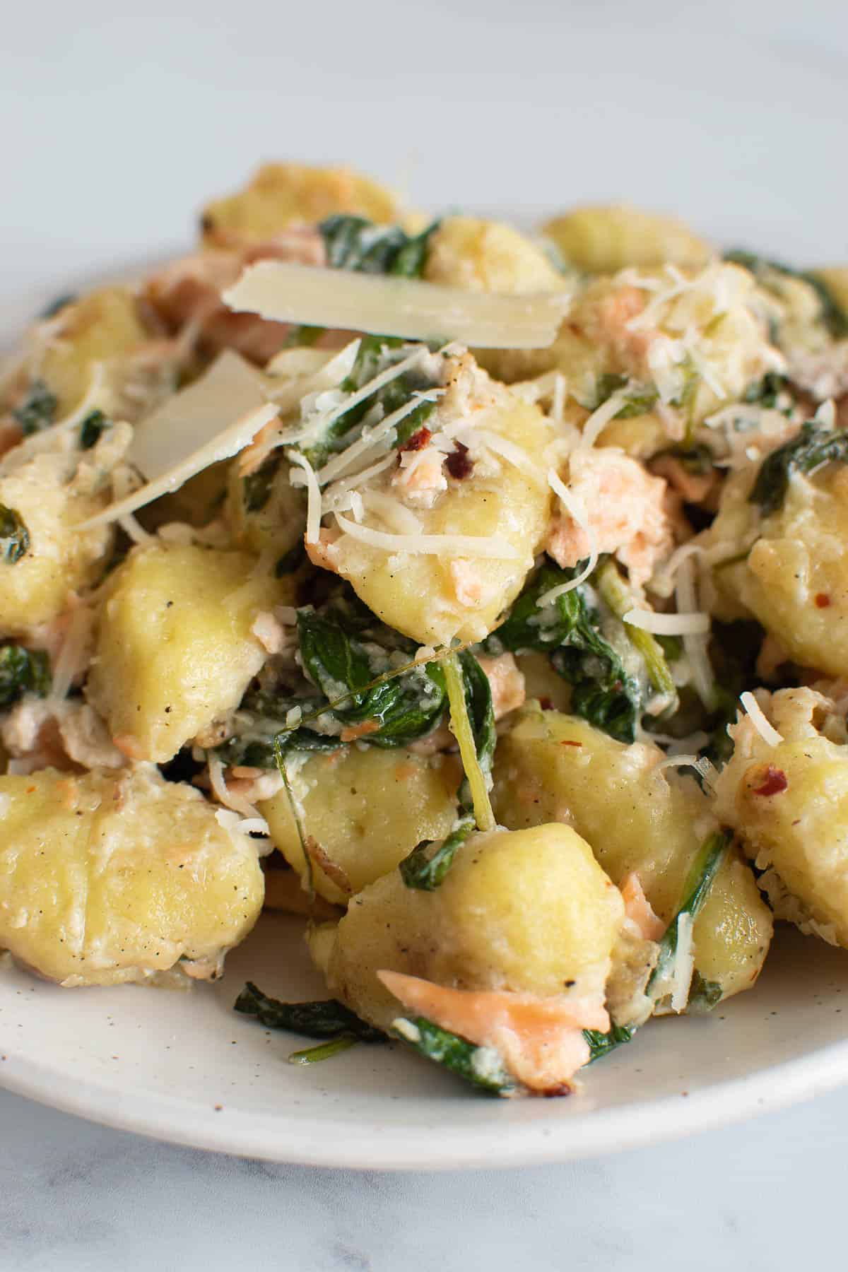 A plate of creamy spinach and salmon gnocchi.