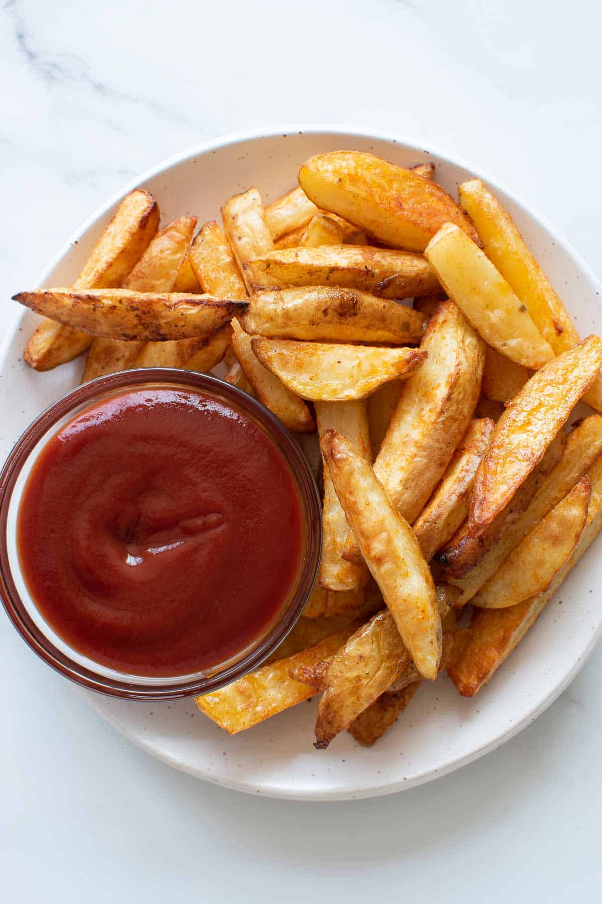 Skin on baked french fries and ketchup.