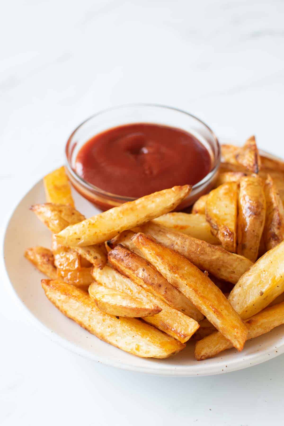 Baked french fries and ketchup.