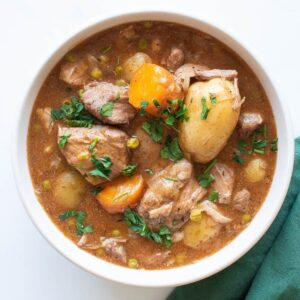 A bowl of pork stew with carrots and potatoes.