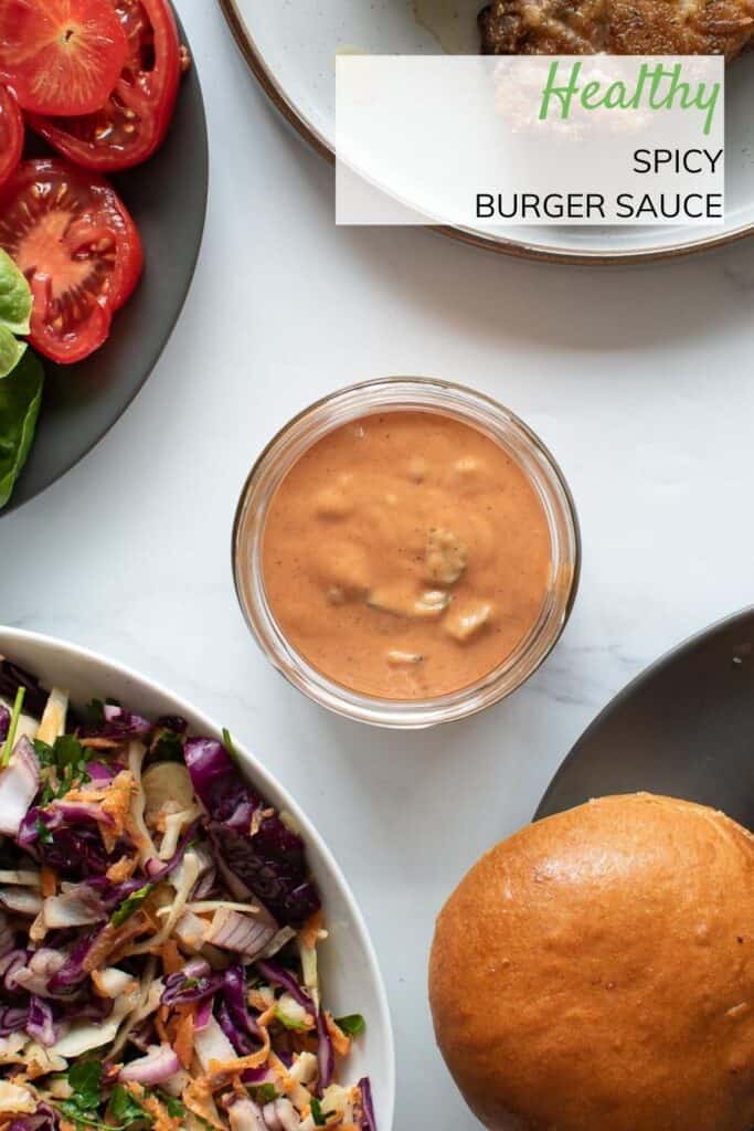 Spicy burger sauce on a table with side dishes and burgers.