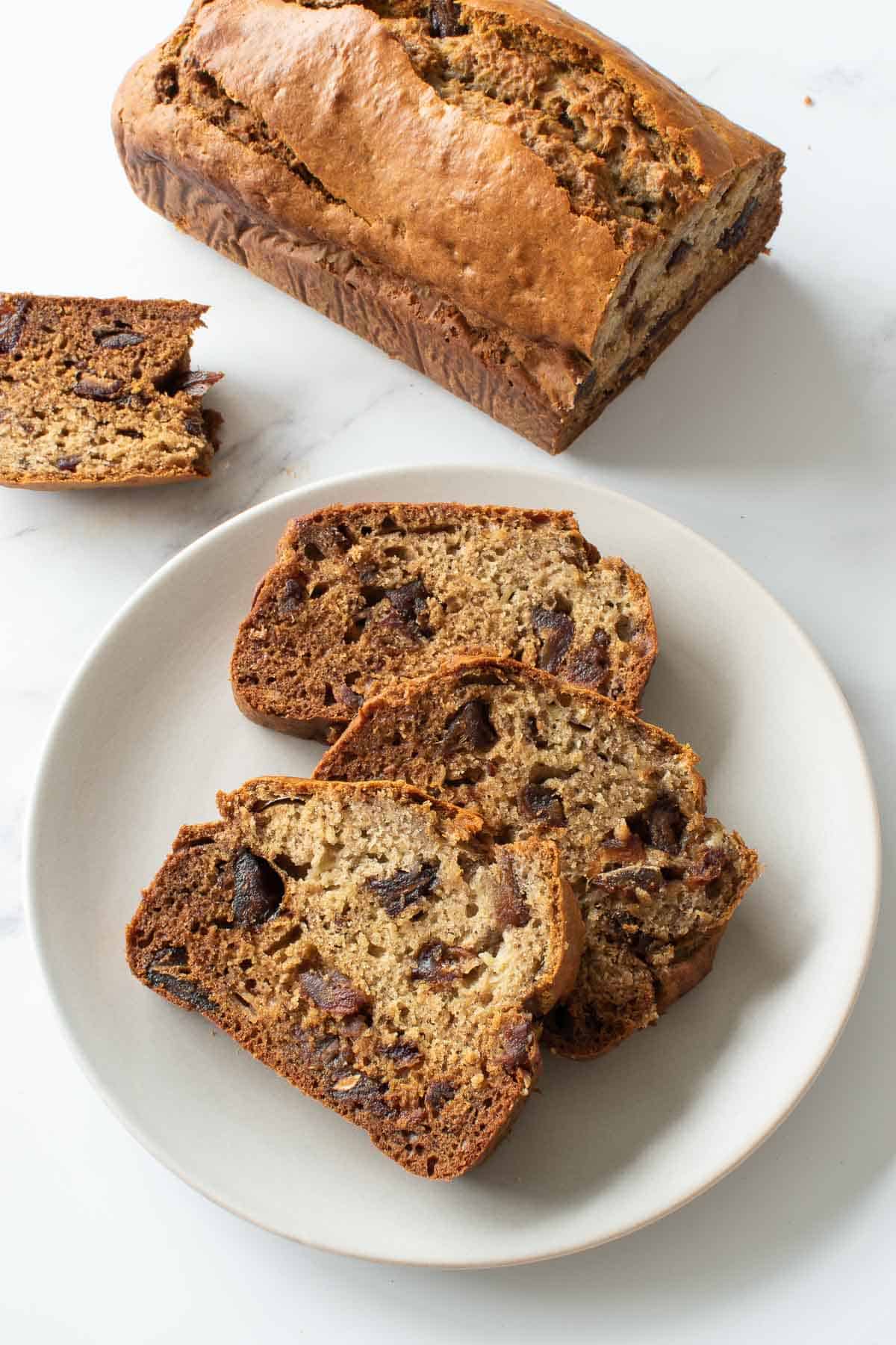 Sliced banana date bread, with a loaf in the background.