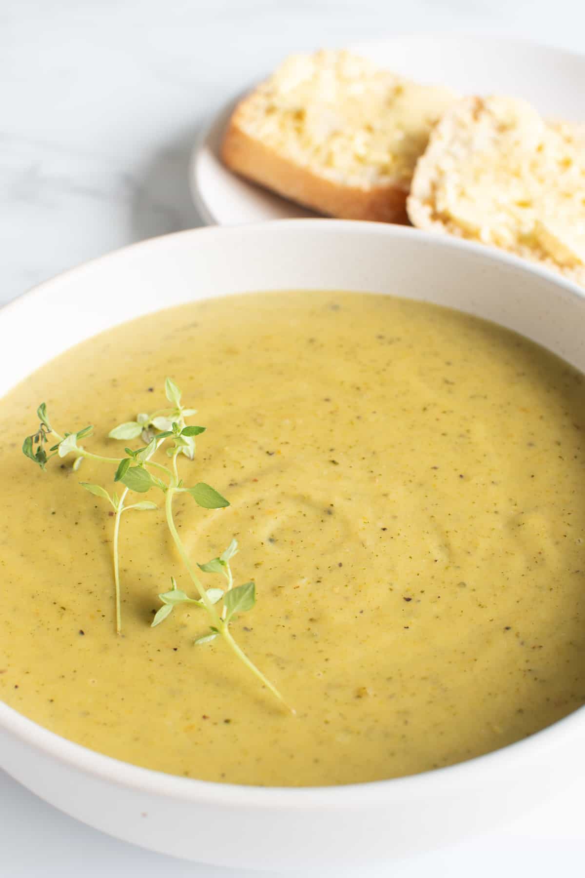 Pressure cooked broccoli soup with bread in the background.