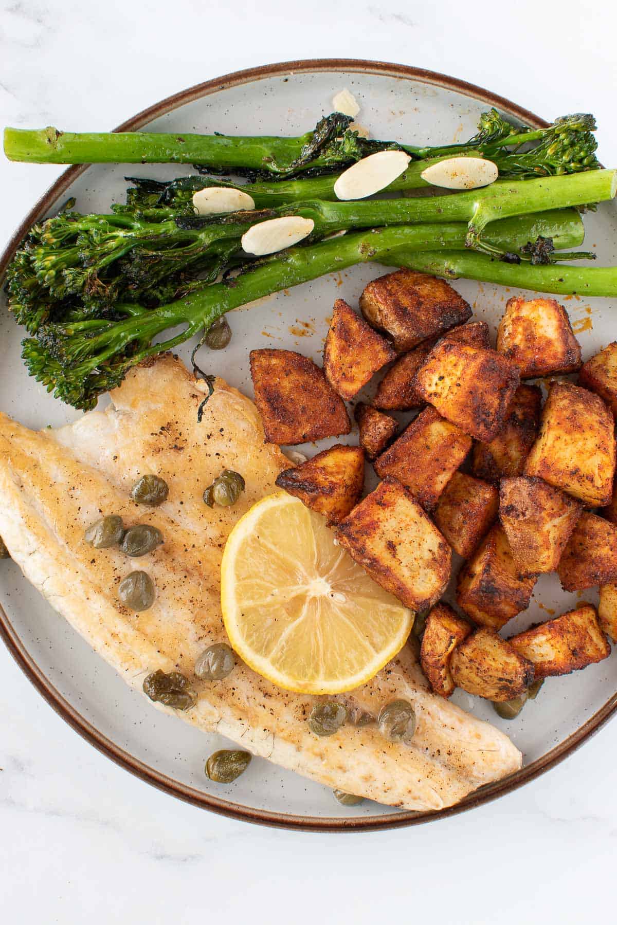 Sea bass, potatoes and broccoli on a plate.