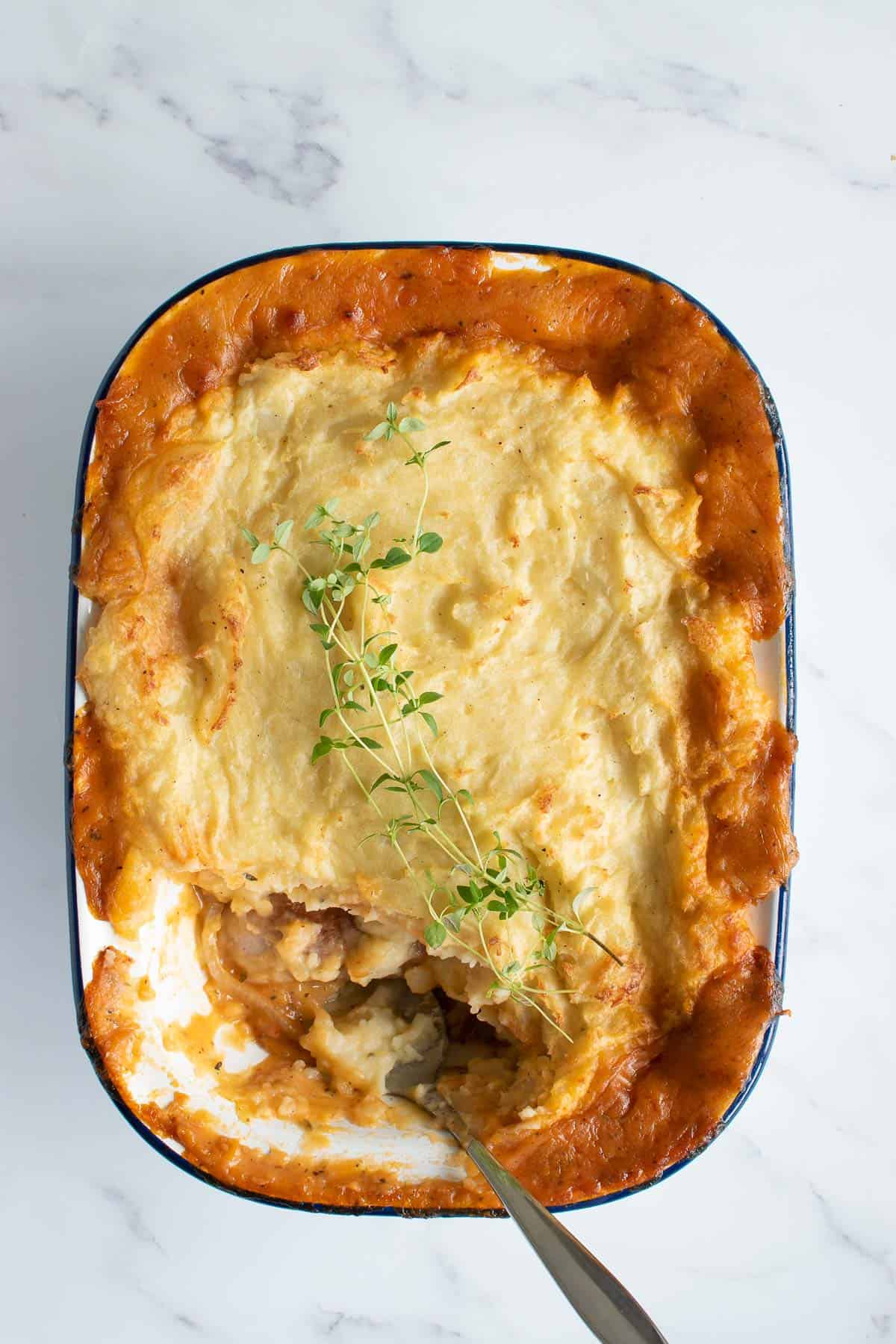 Sausage and mash pie, with a small serving removed from the dish.